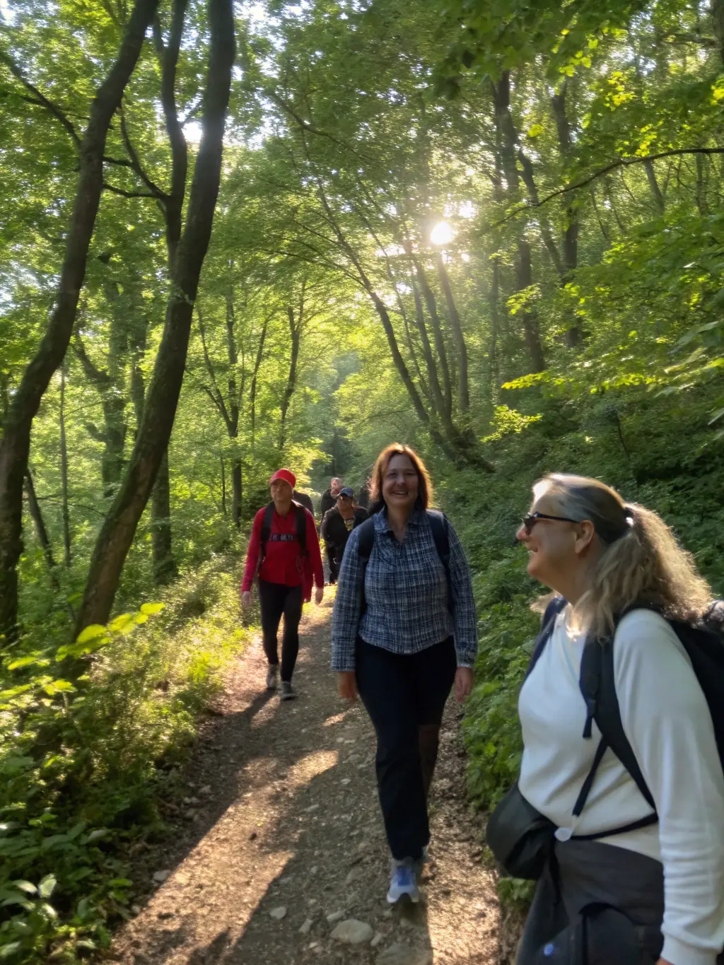 A vibrant photograph capturing participants engaged in a hiking activity through a lush, green trail in the rural areas of Saint-Etienne-de-Maurs, showcasing the outdoor sports program.